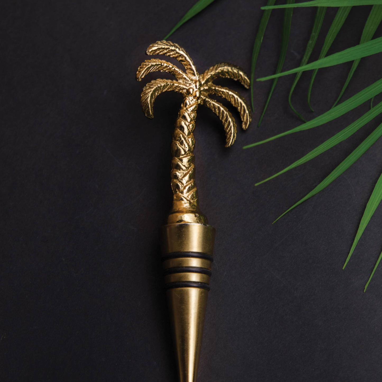 Palmboom-flessenstop op donkere achtergrond met palmbladeren – een eyecatcher voor tropisch geïnspireerde bars, stijlvolle tafels of cadeau-ideeën – verkrijgbaar bij Sherlocks Place.