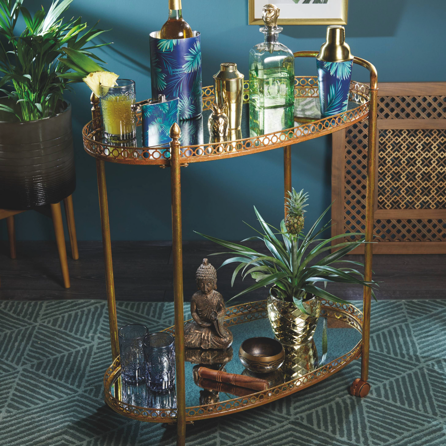 (op een bar trolley met accessoires):
De tropische glazen karaf schittert tussen gouden baraccessoires op een stijlvolle trolley – perfect voor een sfeervolle cocktailavond. Verkrijgbaar bij Sherlocks Place.