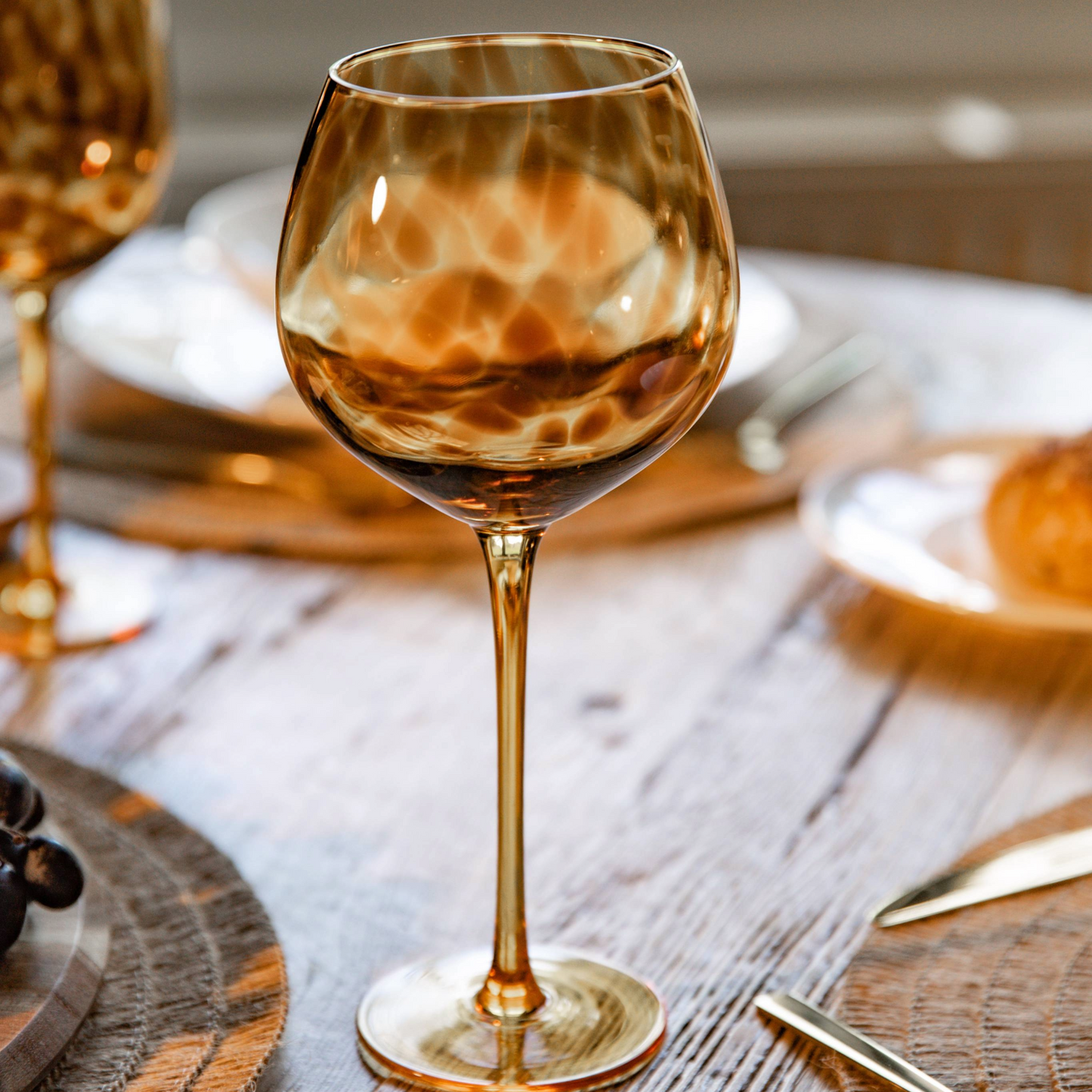 Gedekte tafel met een stijlvol gin glas in het middelpunt, gouden bestek en zachte sfeeraccenten op de achtergrond. Verkrijgbaar bij Sherlocks Place.