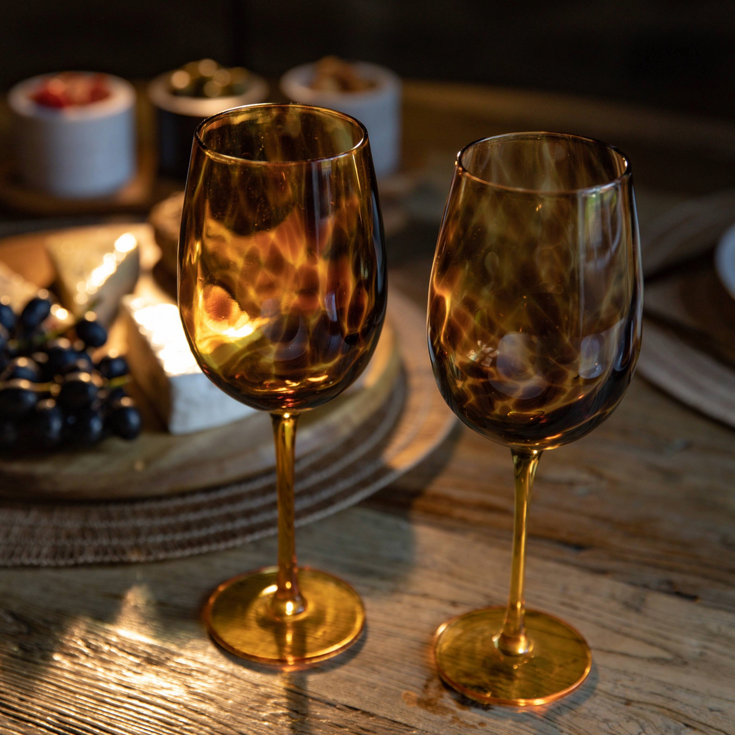 Twee luxe BarCraft wijnglazen met tortoise shell design in sfeervol avondlicht met kaasplank – perfect als exclusief cadeau bij Sherlock’s Place Rotterdam.
