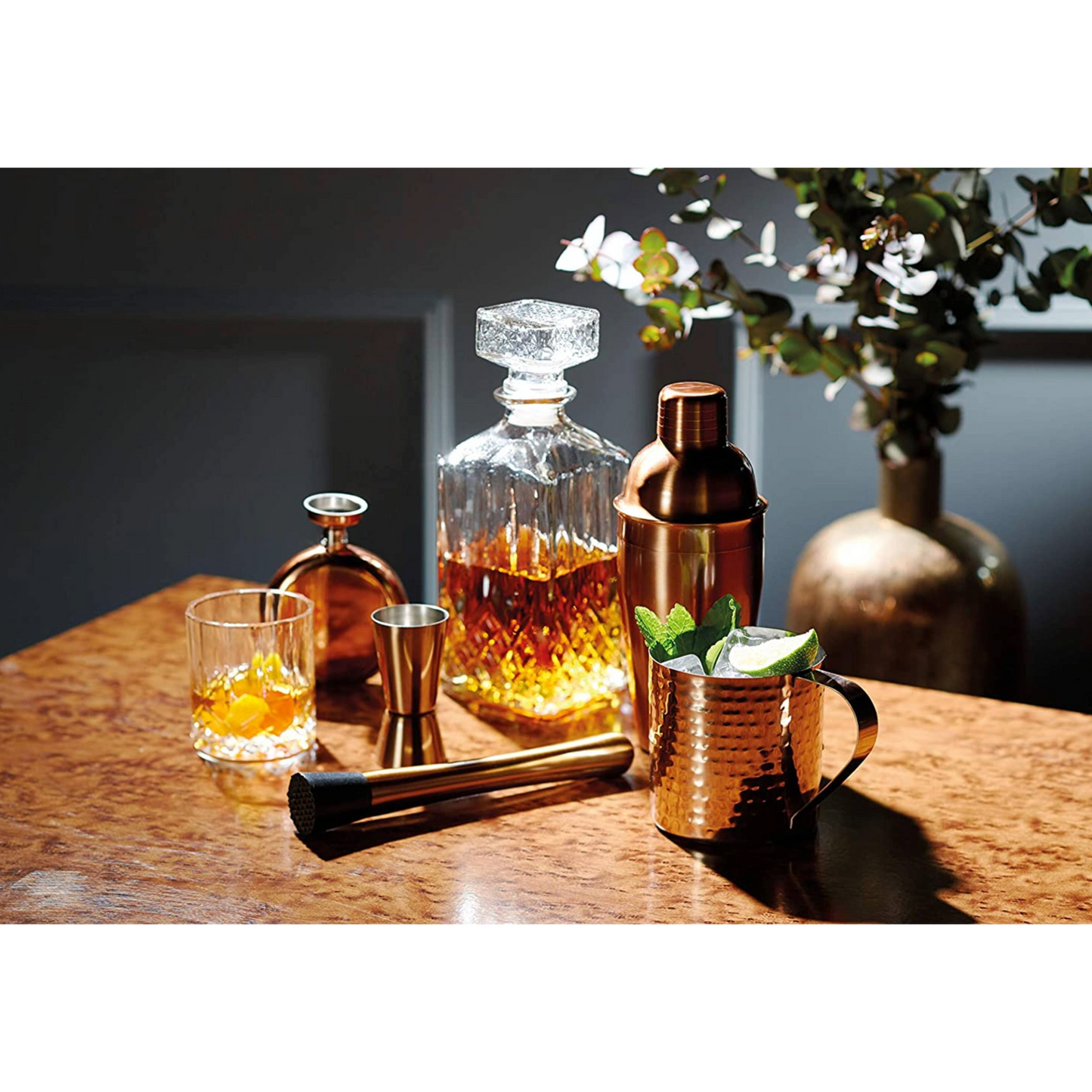 Sfeervolle barsetting met luxe drankaccessoires, waaronder een koperkleurige heupfles – perfect voor de liefhebber van sterke drank. Verkrijgbaar bij Sherlocks Place.