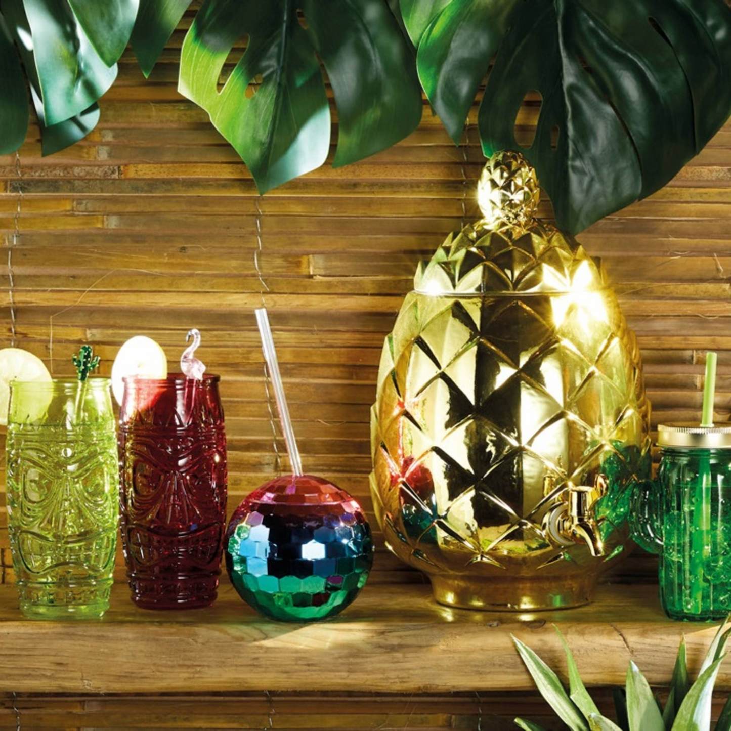 Tropische party setting met tiki bekers en gouden ananasdrankdispenser, aangevuld met de kleurrijke disco bal beker. Dé must-have voor zomerfeestjes. Verkrijgbaar bij Sherlocks Place.