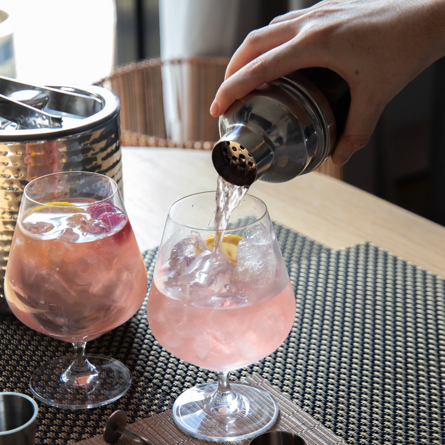 Hand schenkt cocktail uit de BarCraft shaker in een gin-tonic glas, perfect voor thuisgebruik en feestelijke gelegenheden – ideaal cadeau voor cocktailfans. Verkrijgbaar bij Sherlocks Place.