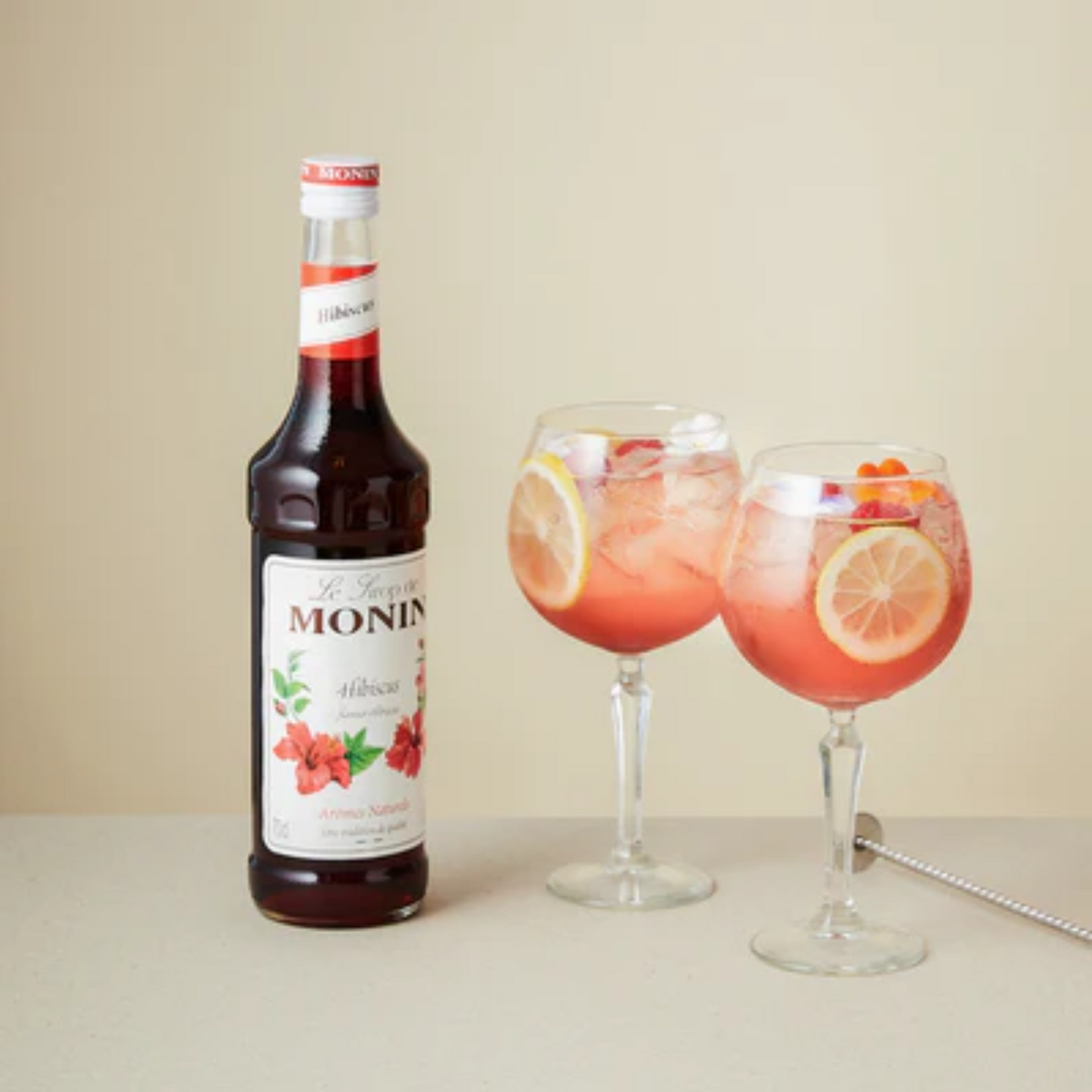Twee verfrissende Gin Tonic cocktails met MONIN Hibiscus siroop, geserveerd met ijs, schijfjes citroen en kleurrijke garnering – de perfecte florale twist voor je zomerse aperitiefmoment. Verkrijgbaar bij Sherlocks Place Rotterdam