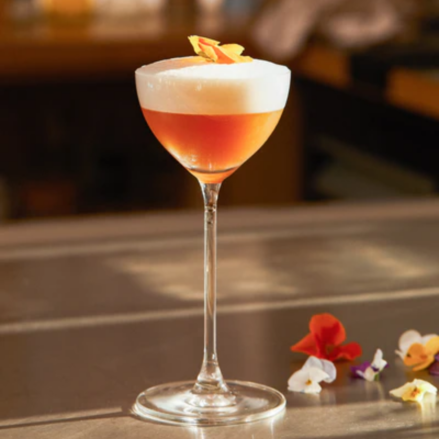 Elegant geserveerde cocktail met schuimlaag en eetbare bloemen. Monin Green Tea concentraat verkrijgbaar bij Sherlocks Place Rotterdam.