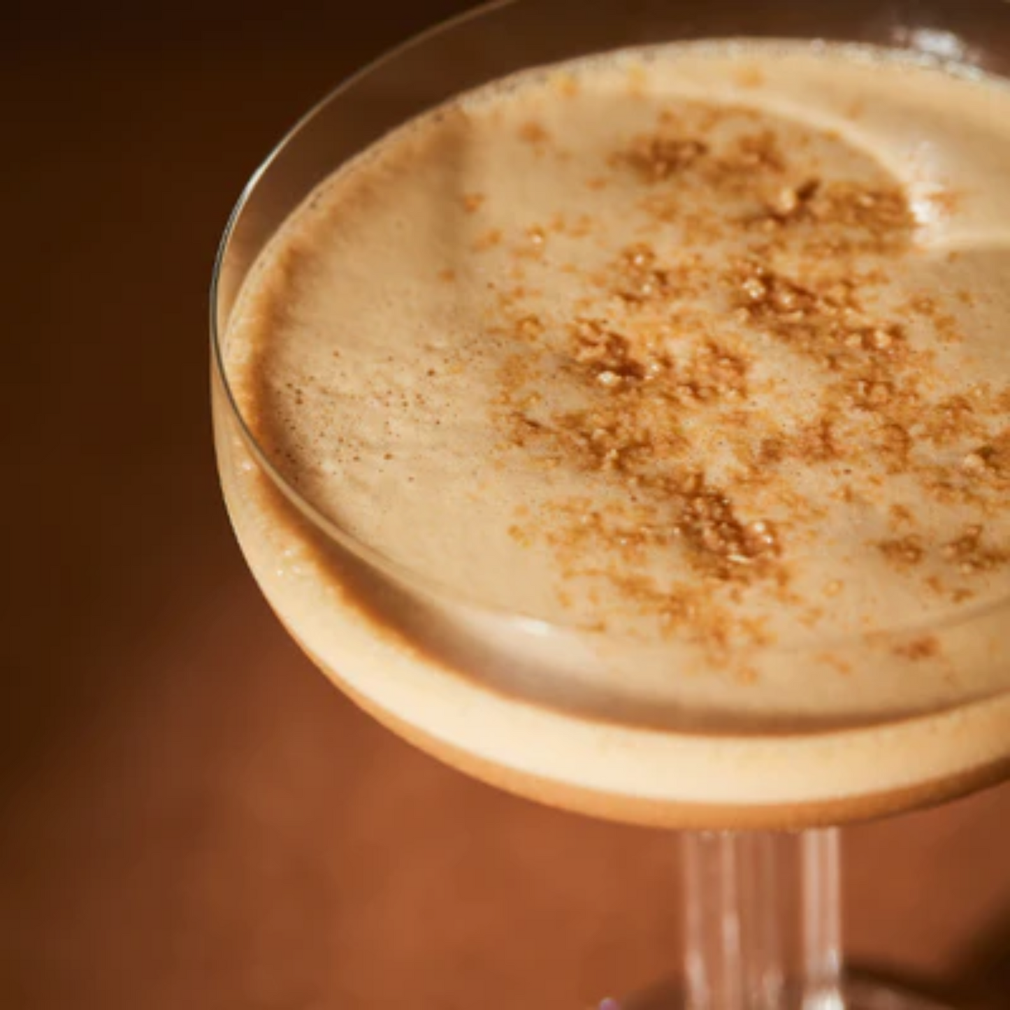 Zeer chique close-up foto van een Espresso Martini. Mooie bruine achtergrond. De close-up is vanaf de bovenkant genomen en laat een mooie creme kleurige schuimlaag zien van de martini. Onder andere met ingredienten van Monin gemaakt. Compleet assortiment Monin is verkrijgbaar bij Sherlocks Place Rotterdam.