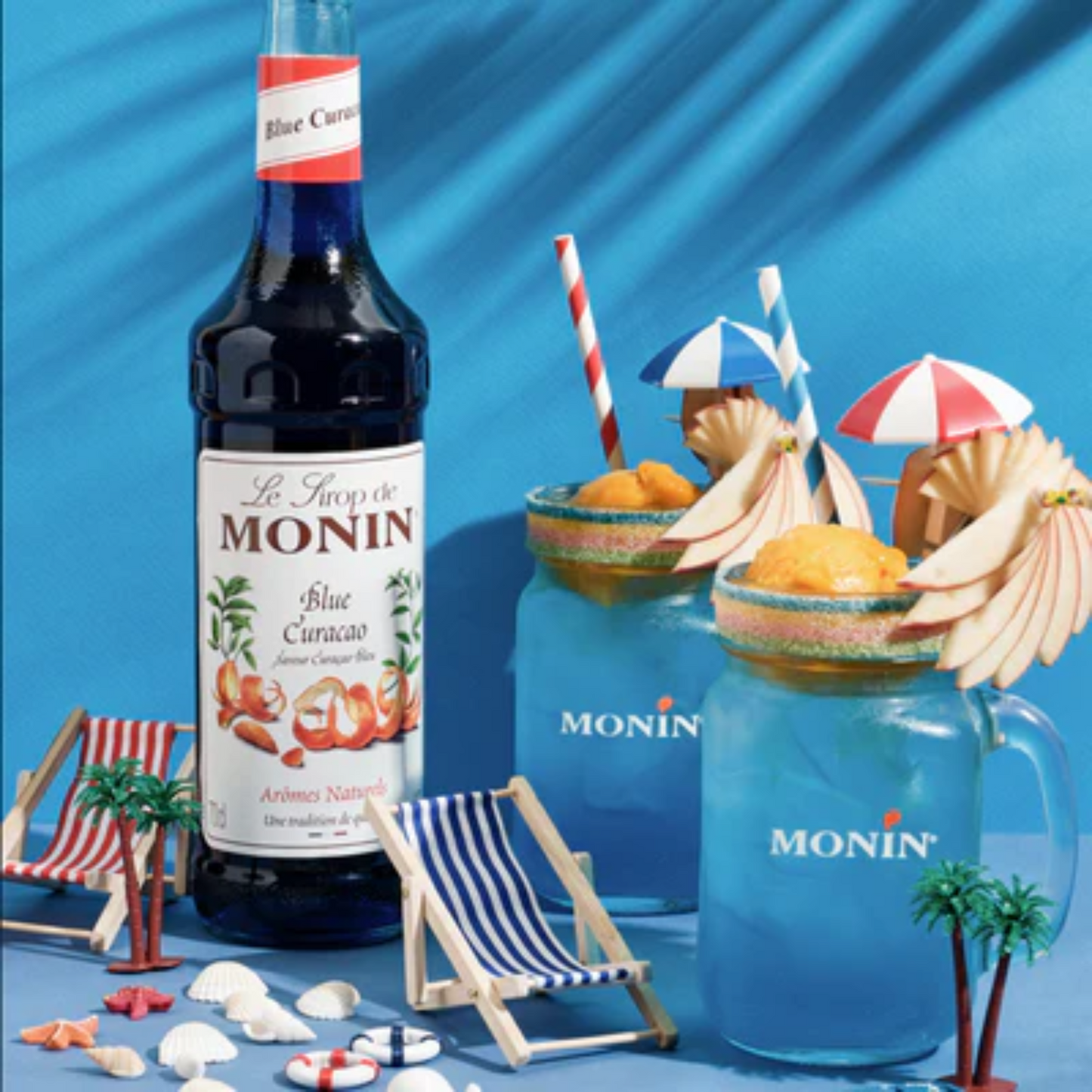 Zomerse Monin Blue Curaçao mocktails geserveerd in Monin jars met fruitgarnituur, mini-parasol en kleurrijke stranddecoratie – perfect voor verfrissing bij Sherlock’s Place in Rotterdam.