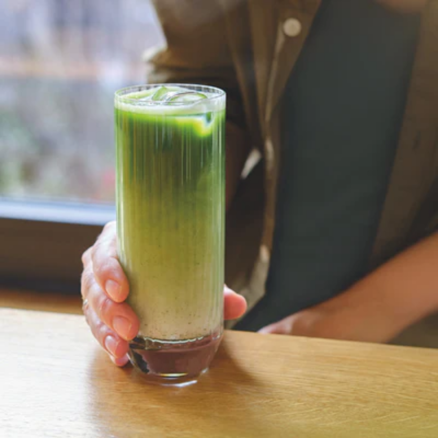 Verfrissende mocktail met lagen matcha, melk en MONIN Mango Siroop, geserveerd in een hoog glas met ijs – perfect voor tropische vibes en zomerse drankjes. Monin verkrijgbaar bij Sherlocks Place Rotterdam
