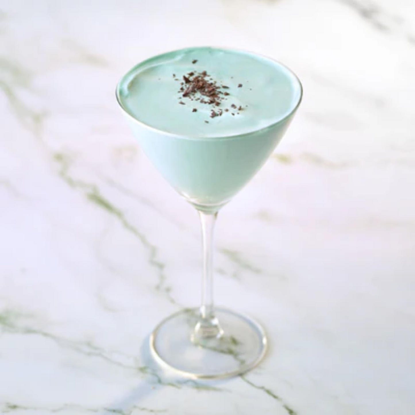 Romige After Dinner Virgin mocktail in martiniglas, met groene munt en witte chocolade, gegarneerd met chocoladeschaafsel – verfrissende non-alcoholische creatie van Monin. Monin verkrijgbaar bij Sherlocks Place Rotterdam