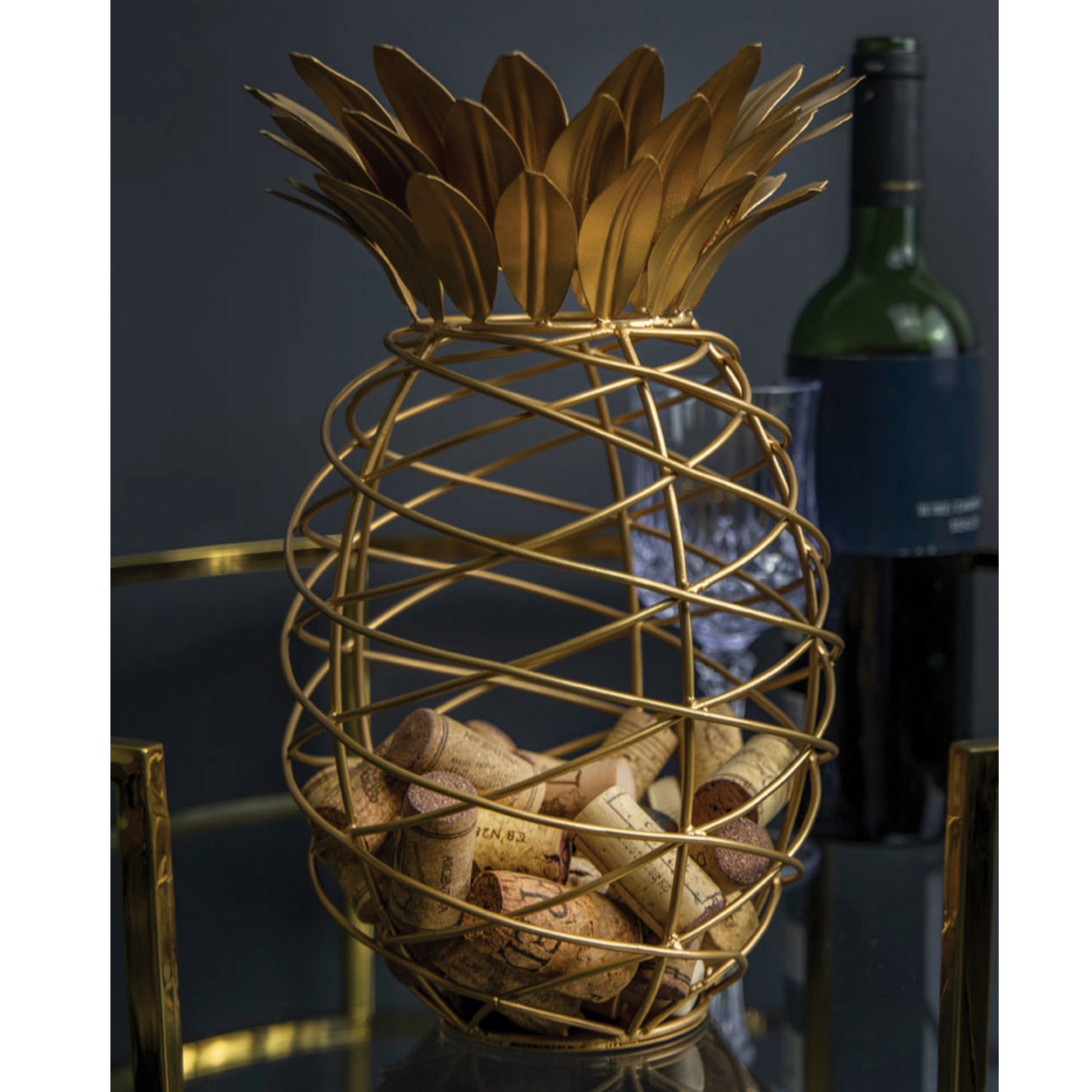 Sfeervol ingerichte gouden ananas kurkenhouder op een bar met wijnfles – perfect accessoire voor wijnbars, horeca en lifestylefoto’s, verkrijgbaar bij Sherlocks Place.
