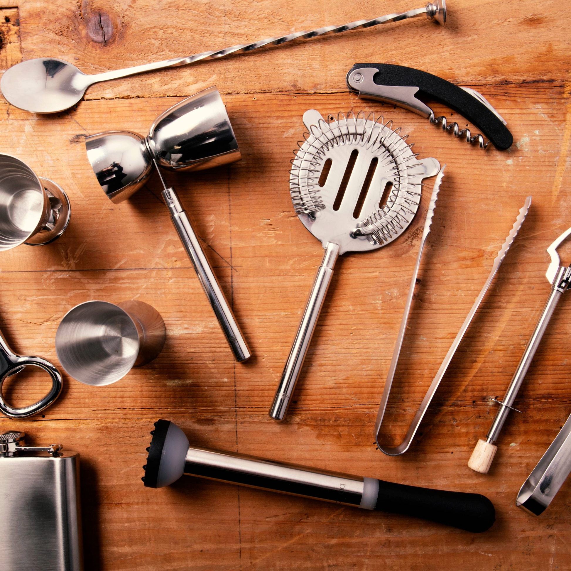 Dubbele jigger van BarCraft op houten barblad tussen essentiële bartools – must-have voor bartenders, entertainers en liefhebbers van cocktails, verkrijgbaar bij Sherlocks Place.