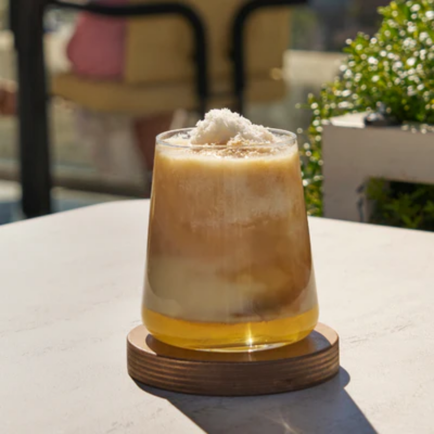 Een mooie Close-up foto van een glas Pina Colada Cold Brew. Een heel makkelijk en zeer lekker zomers recept. Gebruik Monin concentraat Cold Brew, Monin siroop Pina Colada alcoholvrij en een kokosmelk en in een  handomdraai staat er fantastische iced latte op tafel. Op de foto zie je de zon mooi schijnen op het glas. Monin verkrijgbaar bij Sherlocks Place Rotterdam