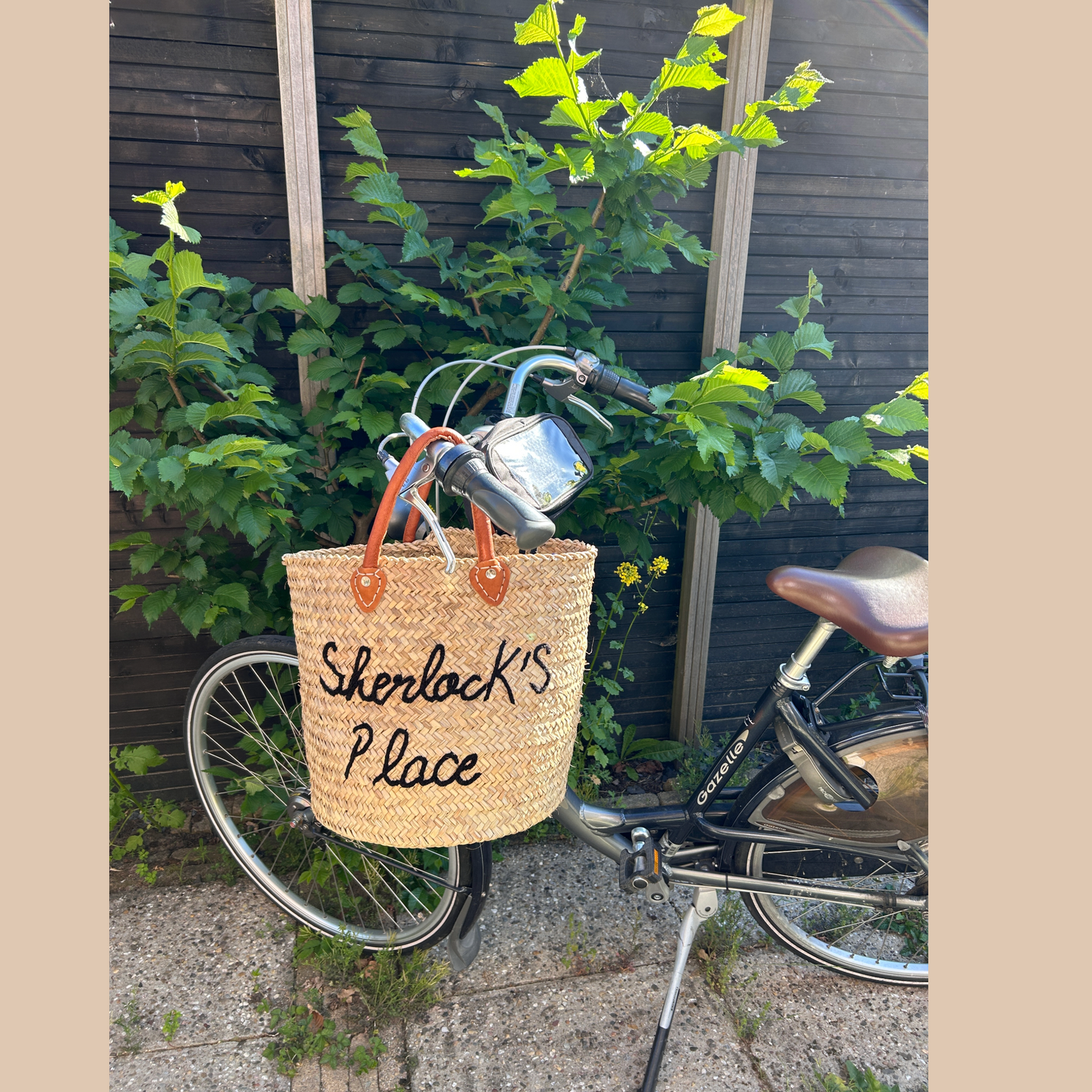 Rieten tas "Sherlock's Place" bevestigd aan een fiets – perfect voor een duurzame en modieuze boodschap of dagje uit.